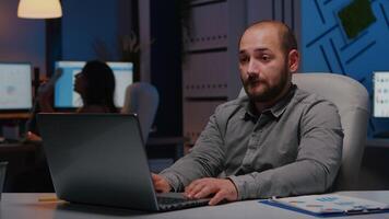 Happy cheerful businessman working in startup company office late at night enjoying online job promotion. Smart executive manager analyzing executive business corporate project video