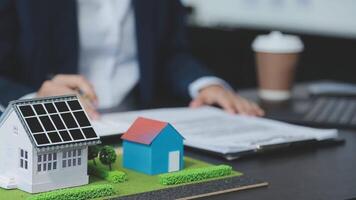 Architecture team and engineer are discussing and brainstorming on floor plan over the clean energy and power saving house design using solar panel for green industry and futuristic home development video