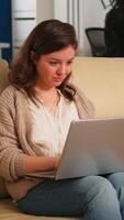 Manager woman searching on laptop sitting in relax zone on confortable couch typing on pc smiling while diverse colleagues working in background. Multiethnic coworkers planning new financial project video