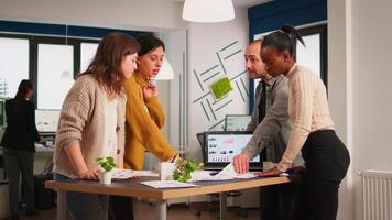 Diverse business people communicating in start up business office standing over desk looking through financial documents. Multiethnic team analysing company informations in modern workplace video