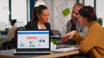Business woman talking about financial project, taking notes, discussing start up ideas using laptop. Diverse employees gathered in co-working, working process in busy company, teamwork help concept video