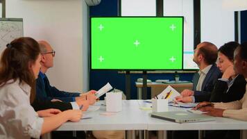 Group of business people discussing company plan with mockup tv green screen in front of desk, ready for financial project presentation. Multiethnic team using mock up monitor with chroma key display video