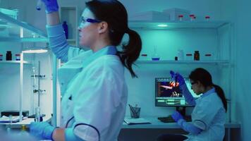 Microbiologist biotechnology researchers working for vaccine development late at night in chemistry equipped laboratory. Doctors examining virus evolution using high tech researching diagnosis video