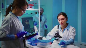 Team of positive scientists working in chemistry equipped laboratory, nurse typing on tablet. Group of doctors examining vaccine evolution using high tech researching diagnosis against covid19 virus video