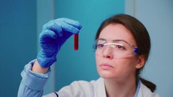 Scientist woman examining blood samples and liquid working in modern equipped laboratory. Team of doctors analysing vaccine evolution using high tech researching diagnosis against covid19 video
