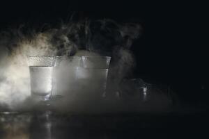 Vodka in shot glasses on dark background photo