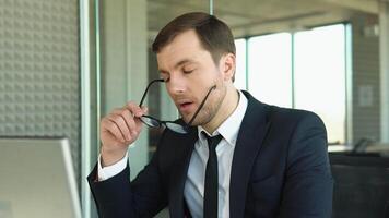 Stressed young man suffering from muscles tension, having painful head feelings due to computer overwork or sedentary working lifestyle. Tired employee overwhelmed with tasks in office video