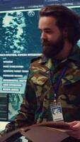 Vertical Staff sergeant providing mission files to brief his operational crew, working on gathering intelligence from surveillance systems. Prepares for various combat scenarios and outcomes. Camera B. video