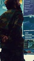 Vertical Colonel overseeing special operation to gather intelligence in control center with CCTV surveillance information on a big screen. Specialist targeting enemy military power base. Camera B. video