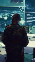 Vertical Commander and his crew operating radar systems via CCTV and satellite to detect and track enemy aircraft or missiles. Military officer uses big screen in control center to guarantee safety. Camera B. video