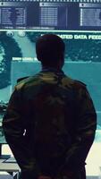 Vertical Staff sergeant monitoring satellite live imagery on a big screen, gathering information for future military operations. Army officer employs reconnaissance system in command post. Camera B. video