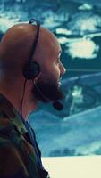 Vertical Male IT specialist operating on reconnaissance system to transmit real time data for new field mission, working in military command center. Telecommunications operator provides air support. Camera B. video