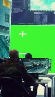 Vertical Diverse group of privates operating on a big screen isolated display, looks at a greenscreen and gathering intelligence to help with military operations in command center. Army facility base. Camera B. video