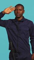 Vertical Security guard doing salute hand gesture, preparing to start job of deterring criminals. Portrait of bodyguard doing greeting gesturing and military pose, studio background, camera B video