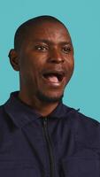 Vertical Headshot portrait of african american security agent isolated against colored studio background. Close up shot of guardian securing assigned post standing over studio backdrop, camera B video