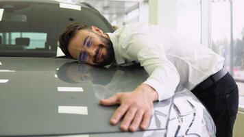Happy Man Hugging Hood Of His New Car, Joyful Smiling Millennial Guy Dreaming About Buying Vehicle In Auto Showroom, Leaning At Surface Of Luxury Automobile, Closeup Shot video