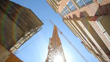 construction crane bottom view. Construction of a house. The sun's rays shine through a construction crane. video