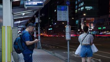 night view timelapse landscape at bus stop in the city center of Taipei capital city of Taiwan with crowded passenger people pedestrian get on get off bus at bus stop video