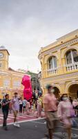 vertical timelapse landscape night view with light illumination on the colonial architecture building with crowded people in Phuket Festival 2023 night time video