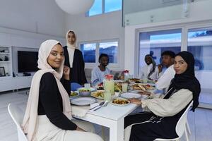 In the sacred month of Ramadan, a Muslim family joyously comes together around a table, eagerly awaiting the communal iftar, engaging in the preparation of a shared meal, and uniting in anticipation photo