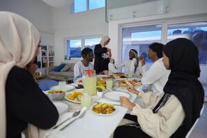 In the sacred month of Ramadan, a Muslim family joyously comes together around a table, eagerly awaiting the communal iftar, engaging in the preparation of a shared meal, and uniting in anticipation photo