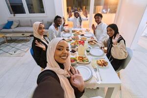 A traditional Muslim family captures the joy of their shared iftar meal during the sacred month of Ramadan through a cheerful family selfie, blending cultural richness, familial togetherness, and the photo