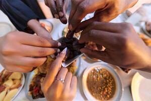 In a poignant close-up, the diverse hands of a Muslim family delicately grasp fresh dates, symbolizing the breaking of the fast during the holy month of Ramadan, capturing a moment of cultural unity photo