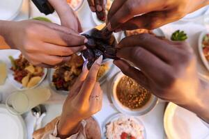 In a poignant close-up, the diverse hands of a Muslim family delicately grasp fresh dates, symbolizing the breaking of the fast during the holy month of Ramadan, capturing a moment of cultural unity photo