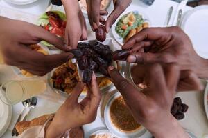 In a poignant close-up, the diverse hands of a Muslim family delicately grasp fresh dates, symbolizing the breaking of the fast during the holy month of Ramadan, capturing a moment of cultural unity photo