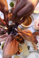 In a poignant close-up, the diverse hands of a Muslim family delicately grasp fresh dates, symbolizing the breaking of the fast during the holy month of Ramadan, capturing a moment of cultural unity photo