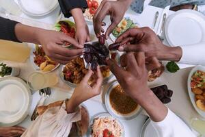 In a poignant close-up, the diverse hands of a Muslim family delicately grasp fresh dates, symbolizing the breaking of the fast during the holy month of Ramadan, capturing a moment of cultural unity photo