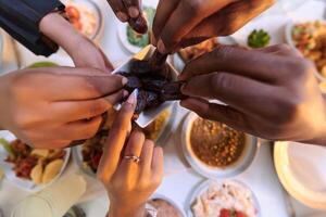 In a poignant close-up, the diverse hands of a Muslim family delicately grasp fresh dates, symbolizing the breaking of the fast during the holy month of Ramadan, capturing a moment of cultural unity photo