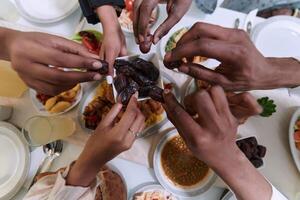 In a poignant close-up, the diverse hands of a Muslim family delicately grasp fresh dates, symbolizing the breaking of the fast during the holy month of Ramadan, capturing a moment of cultural unity photo
