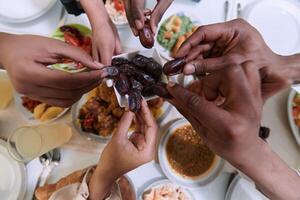 In a poignant close-up, the diverse hands of a Muslim family delicately grasp fresh dates, symbolizing the breaking of the fast during the holy month of Ramadan, capturing a moment of cultural unity photo