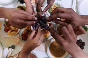 In a poignant close-up, the diverse hands of a Muslim family delicately grasp fresh dates, symbolizing the breaking of the fast during the holy month of Ramadan, capturing a moment of cultural unity photo