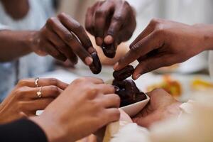 In a poignant close-up, the diverse hands of a Muslim family delicately grasp fresh dates, symbolizing the breaking of the fast during the holy month of Ramadan, capturing a moment of cultural unity photo