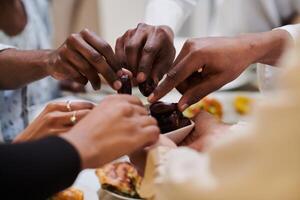 In a poignant close-up, the diverse hands of a Muslim family delicately grasp fresh dates, symbolizing the breaking of the fast during the holy month of Ramadan, capturing a moment of cultural unity photo