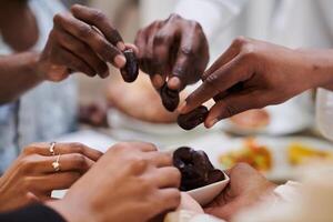 In a poignant close-up, the diverse hands of a Muslim family delicately grasp fresh dates, symbolizing the breaking of the fast during the holy month of Ramadan, capturing a moment of cultural unity photo