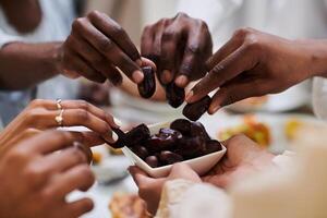 In a poignant close-up, the diverse hands of a Muslim family delicately grasp fresh dates, symbolizing the breaking of the fast during the holy month of Ramadan, capturing a moment of cultural unity photo