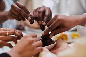 In a poignant close-up, the diverse hands of a Muslim family delicately grasp fresh dates, symbolizing the breaking of the fast during the holy month of Ramadan, capturing a moment of cultural unity photo