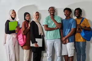 In a vibrant display of educational diversity, a group of students strikes a pose against a clean white background, holding backpacks, laptops, and tablets, symbolizing a blend of modern technology photo