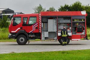 A firefighter meticulously prepares a modern firetruck for a mission to evacuate and respond to dangerous situations, showcasing the utmost dedication to safety and readiness in the face of a fire photo