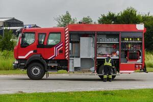 A firefighter meticulously prepares a modern firetruck for a mission to evacuate and respond to dangerous situations, showcasing the utmost dedication to safety and readiness in the face of a fire photo