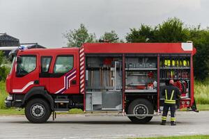 A firefighter meticulously prepares a modern firetruck for a mission to evacuate and respond to dangerous situations, showcasing the utmost dedication to safety and readiness in the face of a fire photo