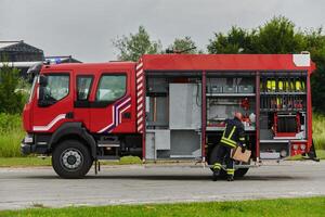 A firefighter meticulously prepares a modern firetruck for a mission to evacuate and respond to dangerous situations, showcasing the utmost dedication to safety and readiness in the face of a fire photo