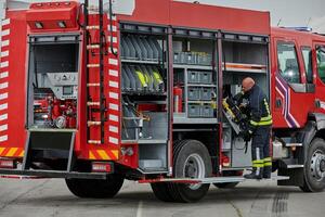 A firefighter meticulously prepares a modern firetruck for a mission to evacuate and respond to dangerous situations, showcasing the utmost dedication to safety and readiness in the face of a fire photo