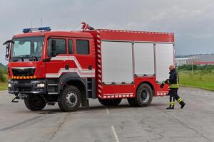 A firefighter meticulously prepares a modern firetruck for a mission to evacuate and respond to dangerous situations, showcasing the utmost dedication to safety and readiness in the face of a fire photo