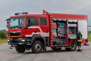 A firefighter meticulously prepares a modern firetruck for a mission to evacuate and respond to dangerous situations, showcasing the utmost dedication to safety and readiness in the face of a fire photo
