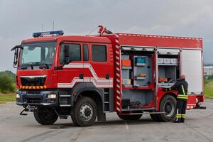 A firefighter meticulously prepares a modern firetruck for a mission to evacuate and respond to dangerous situations, showcasing the utmost dedication to safety and readiness in the face of a fire photo