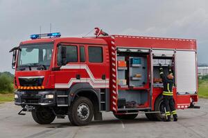 A firefighter meticulously prepares a modern firetruck for a mission to evacuate and respond to dangerous situations, showcasing the utmost dedication to safety and readiness in the face of a fire photo
